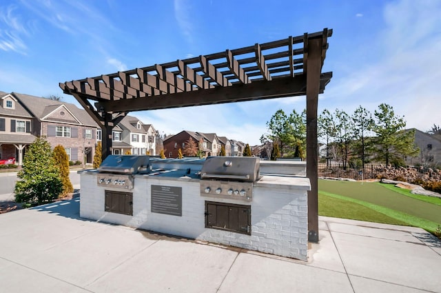 view of patio featuring a pergola, exterior kitchen, grilling area, and a residential view
