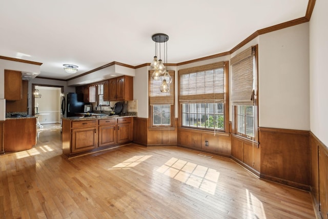 kitchen with crown molding, light wood finished floors, freestanding refrigerator, and brown cabinets