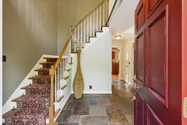 entryway with stairway, baseboards, and stone finish flooring