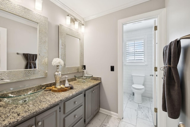 bathroom with a sink, double vanity, marble finish floor, baseboards, and ornamental molding