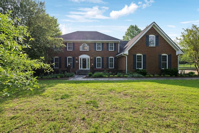 colonial home featuring brick siding and a front lawn