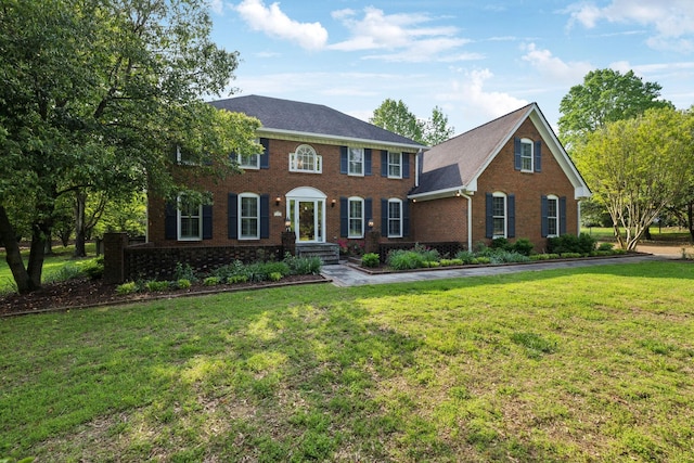 colonial inspired home featuring a front yard and brick siding