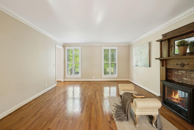 living room featuring baseboards, ornamental molding, a brick fireplace, and wood finished floors