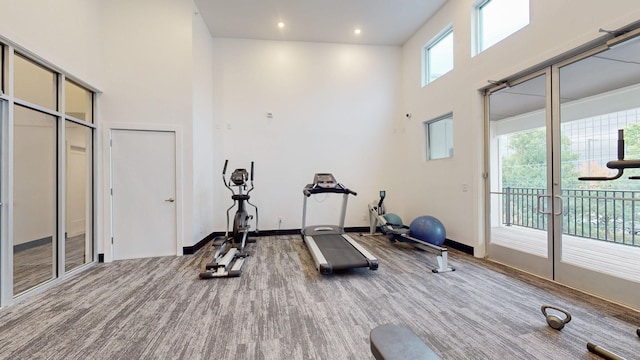 exercise area with carpet floors, recessed lighting, baseboards, and a towering ceiling
