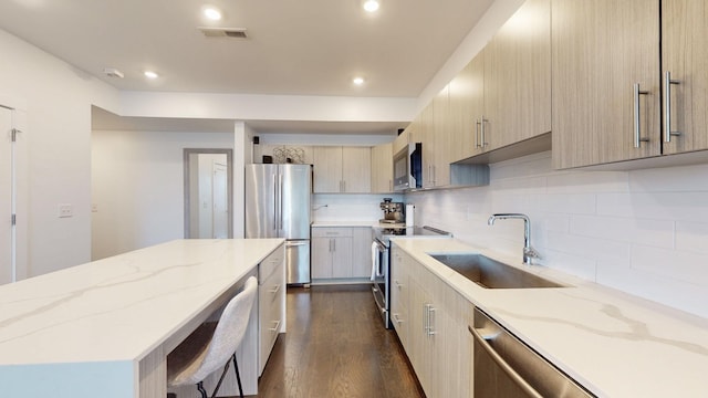 kitchen featuring decorative backsplash, appliances with stainless steel finishes, light stone countertops, a sink, and dark wood-style floors