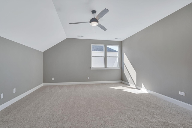 additional living space featuring ceiling fan, light colored carpet, visible vents, vaulted ceiling, and baseboards