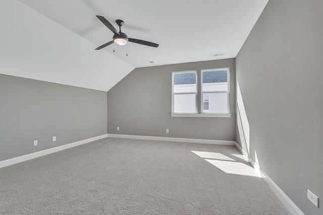additional living space with visible vents, ceiling fan, vaulted ceiling, and light carpet