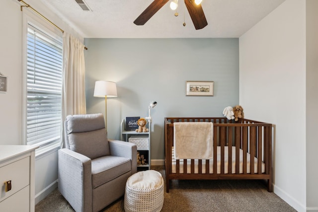 bedroom featuring carpet floors, a crib, visible vents, and multiple windows
