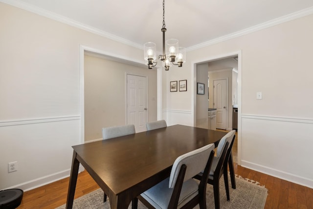 dining space featuring crown molding, baseboards, a notable chandelier, and wood finished floors