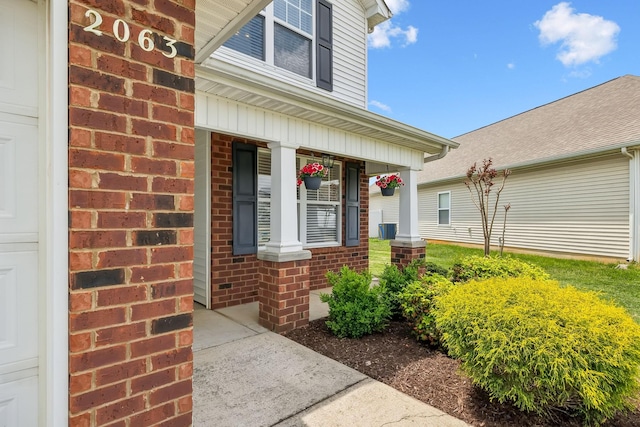 doorway to property with covered porch and brick siding