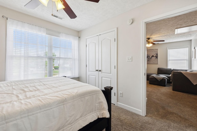 bedroom featuring carpet flooring, a textured ceiling, multiple windows, and a closet