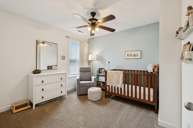 carpeted bedroom with a nursery area, ceiling fan, a textured ceiling, baseboards, and visible vents