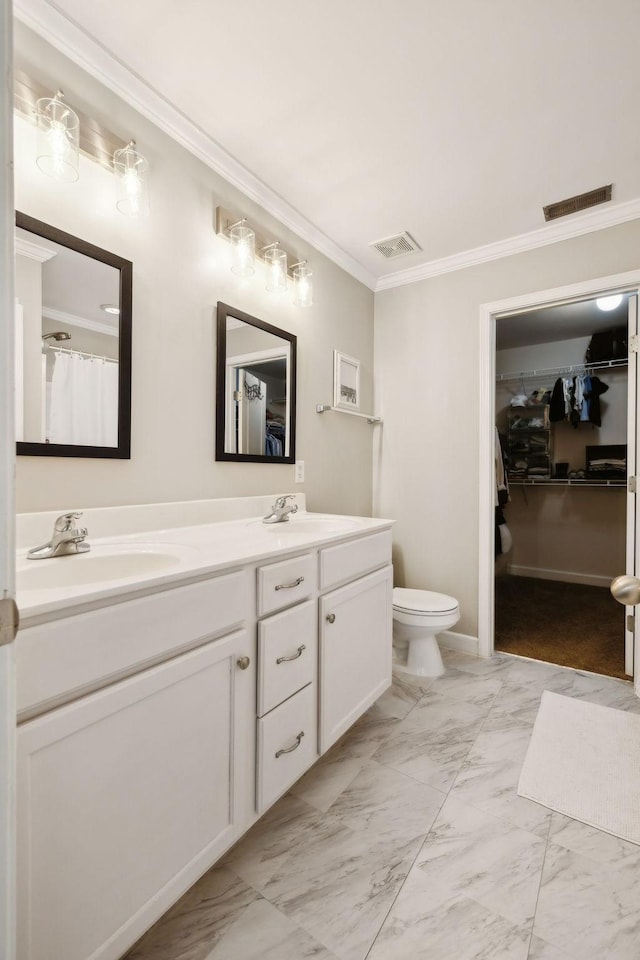 bathroom with double vanity, a walk in closet, visible vents, marble finish floor, and ornamental molding
