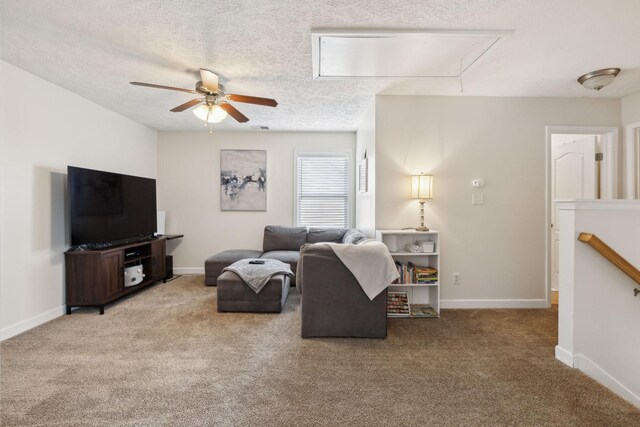 carpeted living room with baseboards, attic access, a textured ceiling, and a ceiling fan