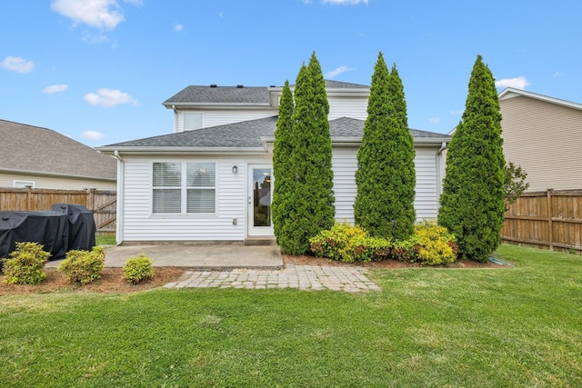 rear view of house with a lawn, roof with shingles, fence, and a patio area