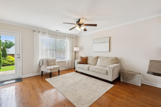 living room featuring crown molding, a ceiling fan, visible vents, and light wood-style flooring