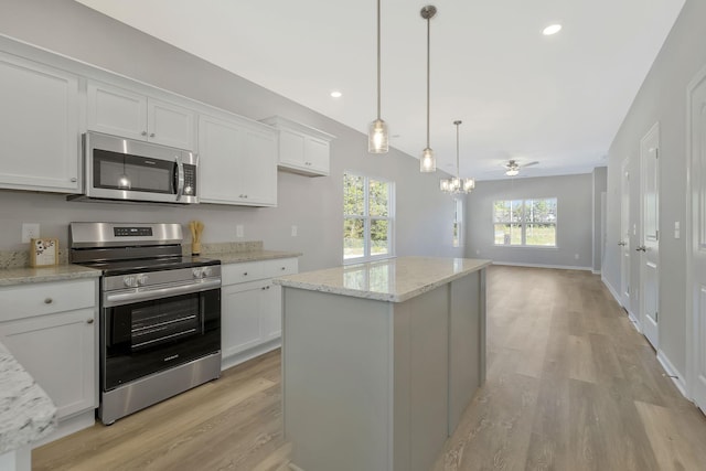 kitchen featuring white cabinets, stainless steel appliances, light stone countertops, and light wood finished floors