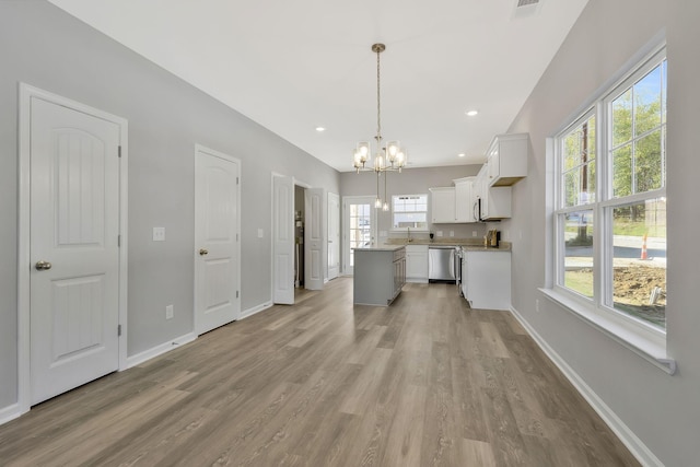 kitchen with white cabinets, a notable chandelier, light wood-style floors, a center island, and stainless steel dishwasher