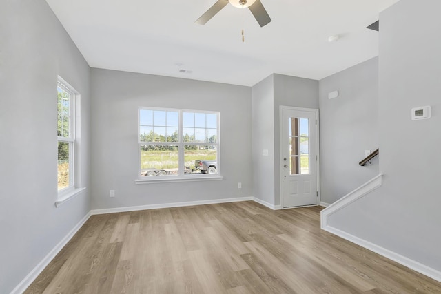 unfurnished living room with baseboards, ceiling fan, and light wood-style flooring
