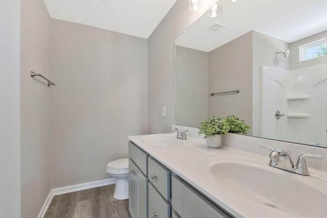 bathroom with a sink, double vanity, toilet, and wood finished floors
