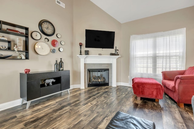 living area featuring visible vents, wood finished floors, baseboards, a tile fireplace, and vaulted ceiling