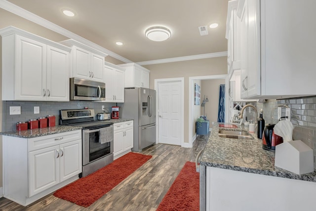 kitchen with a sink, stainless steel appliances, white cabinetry, backsplash, and ornamental molding