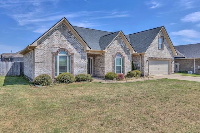french provincial home with brick siding, fence, a front yard, and concrete driveway