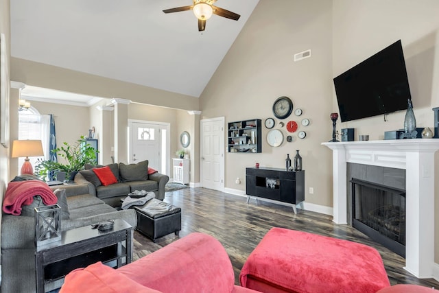 living room with a ceiling fan, visible vents, a tiled fireplace, wood finished floors, and high vaulted ceiling