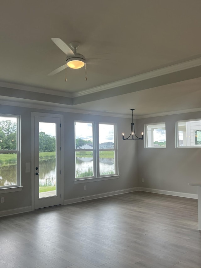 empty room with crown molding, wood finished floors, baseboards, a water view, and ceiling fan with notable chandelier