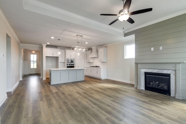 kitchen featuring open floor plan, light countertops, white cabinets, custom range hood, and stainless steel appliances