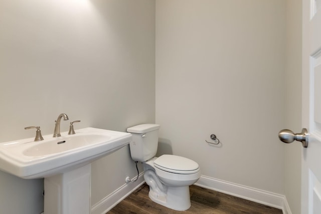 bathroom with toilet, baseboards, and wood finished floors
