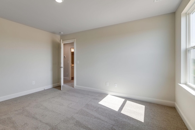 empty room featuring baseboards, a wealth of natural light, and light colored carpet