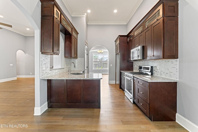 8508 Flowering Peach Ln, Knoxville, TN 37923 - kitchen with arched walkways, appliances with stainless steel finishes, a sink, and light stone counters