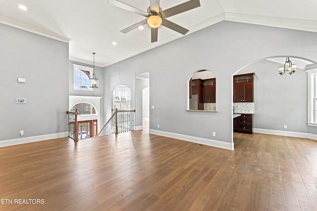 8508 Flowering Peach Ln, Knoxville, TN 37923 - unfurnished living room featuring crown molding, wood finished floors, recessed lighting, arched walkways, and ceiling fan with notable chandelier