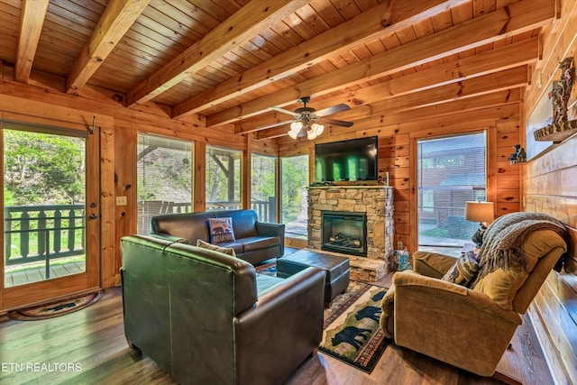 living room featuring wood walls, plenty of natural light, beam ceiling, and wood finished floors