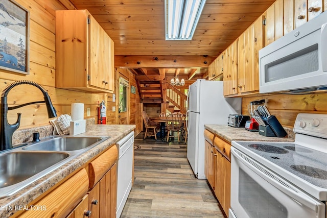 kitchen with white appliances, wood walls, and an inviting chandelier