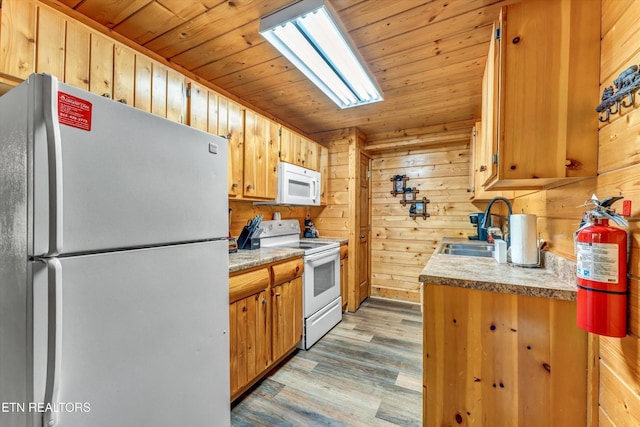 kitchen with wooden walls, a sink, white appliances, light wood-style flooring, and wooden ceiling