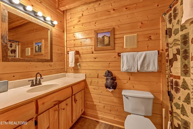 bathroom featuring visible vents, wood walls, toilet, and vanity