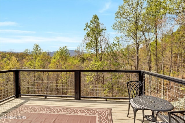 wooden terrace featuring a view of trees