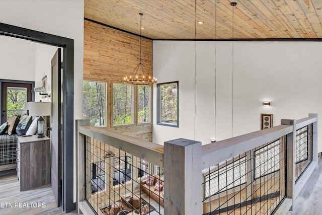 hall with wood ceiling, a towering ceiling, a notable chandelier, and an upstairs landing