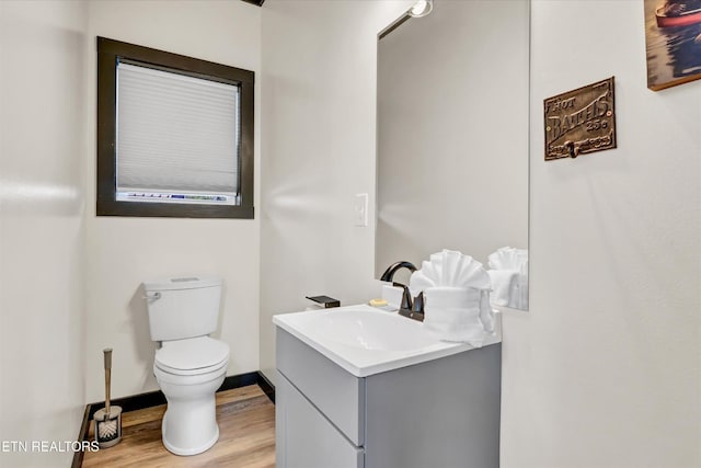 bathroom with vanity, baseboards, wood finished floors, and toilet
