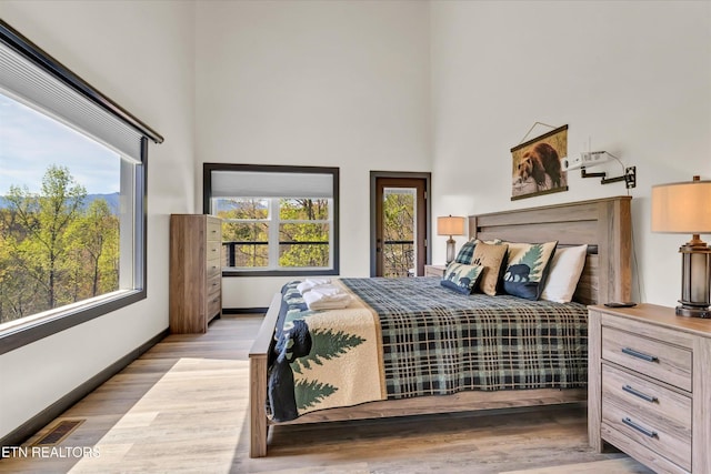 bedroom featuring baseboards, multiple windows, and a towering ceiling