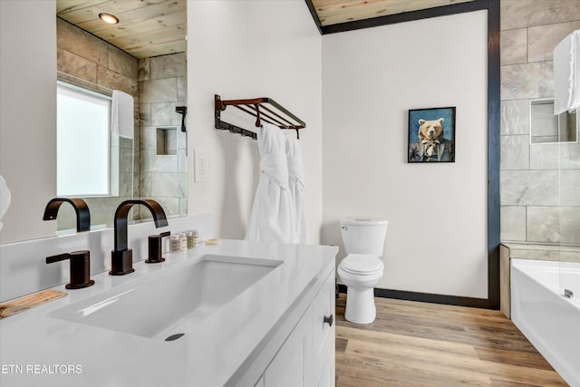 full bath featuring a bath, wood finished floors, vanity, baseboards, and toilet