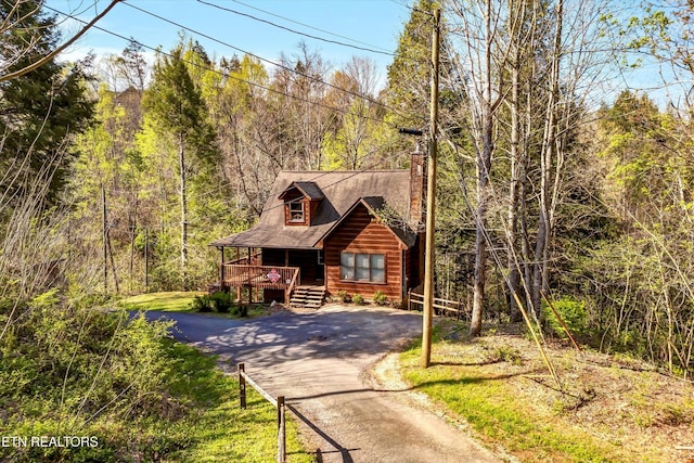 415 Silver Maple Ln, Gatlinburg, TN 37738 - log cabin featuring a chimney, driveway, a wooded view, and covered porch