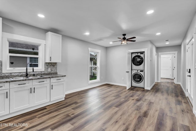 clothes washing area featuring laundry area, a ceiling fan, stacked washer and dryer, a sink, and recessed lighting
