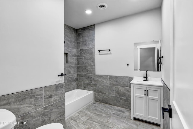 full bathroom with tile walls, a wainscoted wall, vanity, toilet, and marble finish floor
