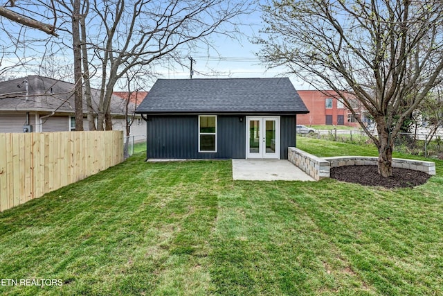 back of property featuring a fenced backyard, a yard, french doors, and a shingled roof
