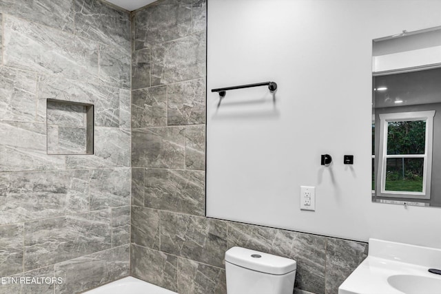 bathroom featuring toilet, tile walls, and a sink