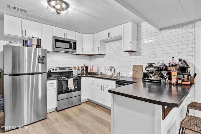 1606 Sexton Ln, Knoxville, TN 37932 - kitchen with visible vents, dark countertops, a sink, a peninsula, and stainless steel appliances
