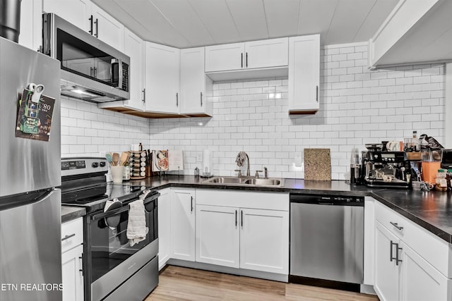 1606 Sexton Ln, Knoxville, TN 37932 - kitchen with dark countertops, appliances with stainless steel finishes, a sink, light wood-style floors, and white cabinetry